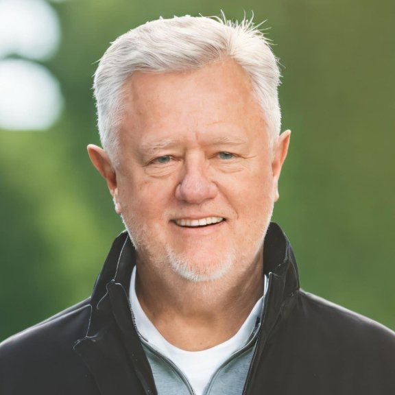 Rustin Carlson, smiling, in a dark zip jacket outdoors